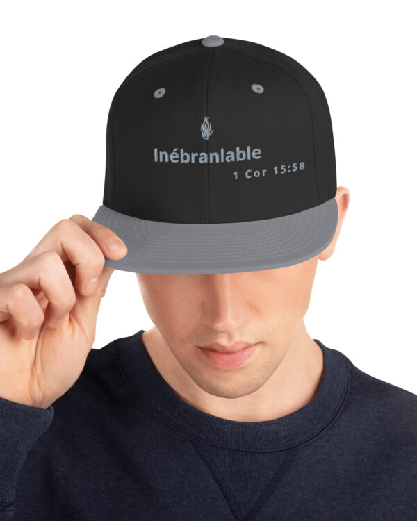 Casquette snapback KHAWNAN noir / argenté, parole « Inébranlable ».